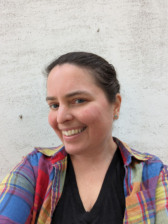 Me smiling in a rainbow Madras shirt in front of a textured stucco wall